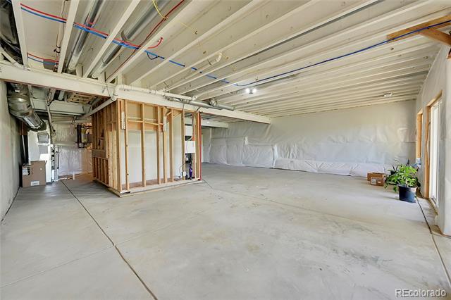 Unfinished garage with a concrete floor, exposed ceiling framing, and a small framed utility enclosure.
