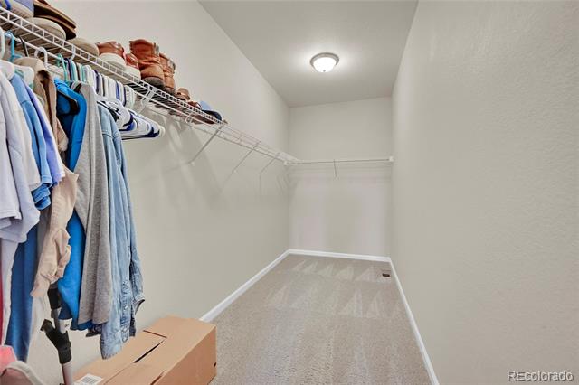 Walk-in closet with wire shelving, hanging clothes, and boxes on the floor.