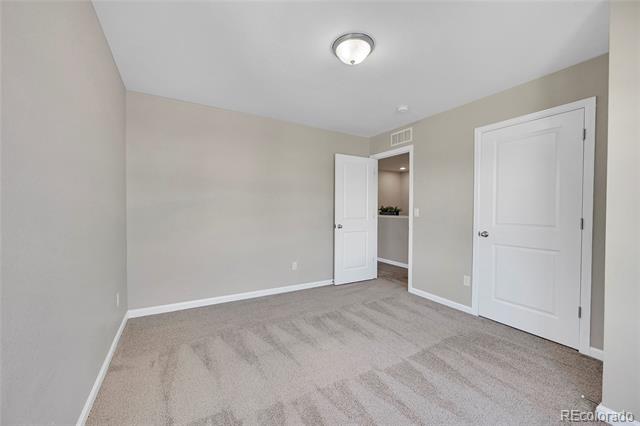 Empty bedroom with beige carpet and an open door to a small closet area.