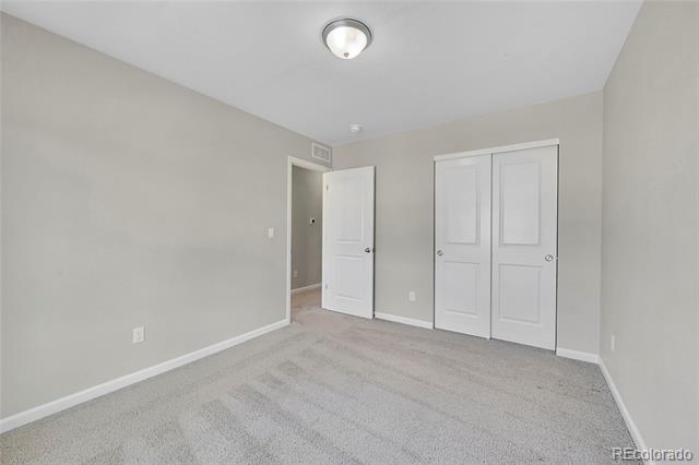 Empty bedroom with beige carpet, double closet doors, and an open doorway.