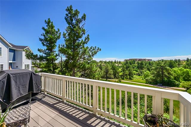 Raised deck with white railings, a covered grill, and views of trees and open space.