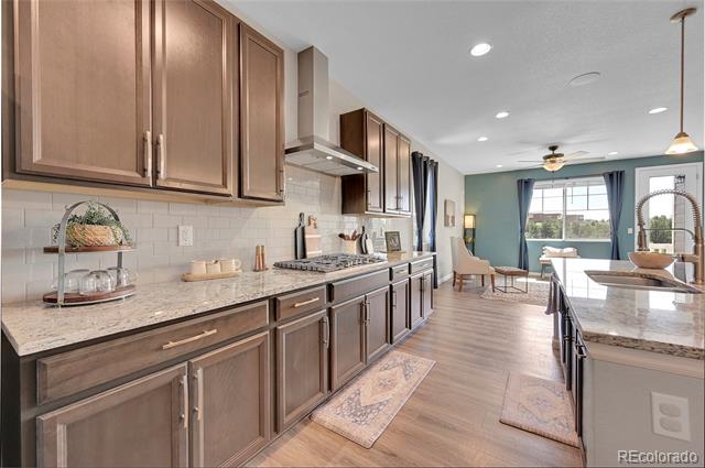 Kitchen with dark wood cabinetry and stone counters opening to a dining and living area.