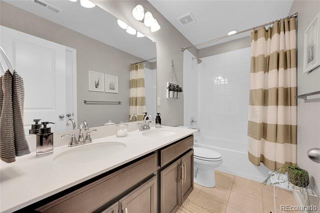 Bathroom with a double-sink vanity, dark wood cabinets, and a tan-and-cream striped shower curtain.