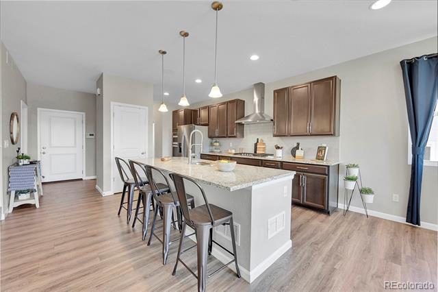 Kitchen with dark wood cabinets, stainless steel appliances, and a granite island with bar seating.