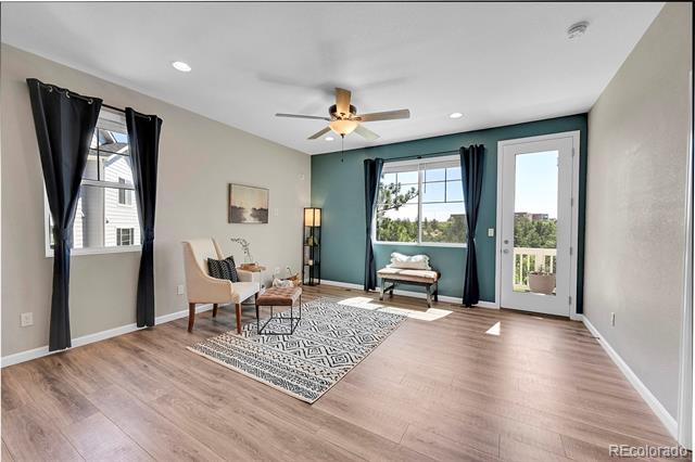 Living room with a teal accent wall, patterned rug, and glass door to a balcony.