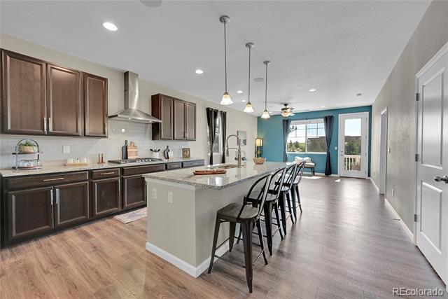Open kitchen with dark wood cabinets, a large island with bar stools, and sliding glass doors.
