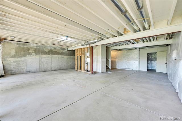 Unfinished garage with a concrete floor, exposed ceiling framing, and an open framed section.