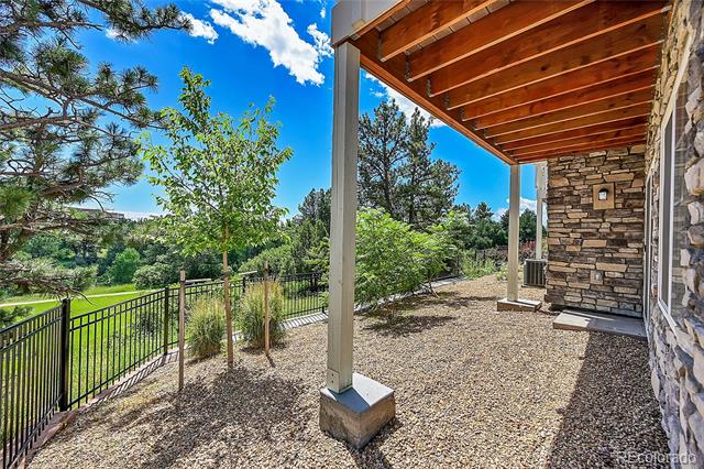 Covered stone-and-wood patio overlooking a fenced, tree-lined yard.