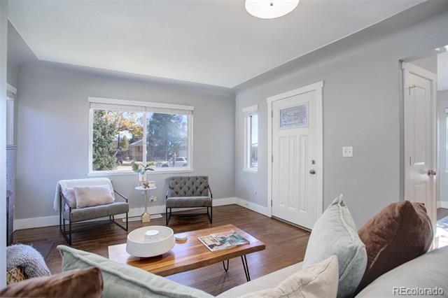 Staged living room with gray walls, a large window, accent chairs, and hardwood floors.