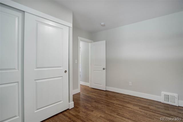 Empty interior room with hardwood floors and several white paneled doors.