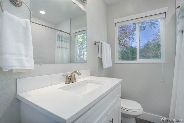 Bathroom with a white vanity and chrome faucet beside a window overlooking trees.