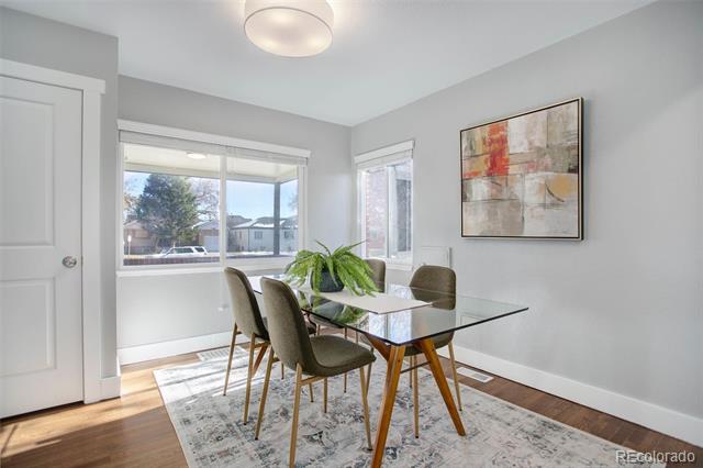 Dining room with a glass-top table, four chairs, large windows, and abstract wall art.