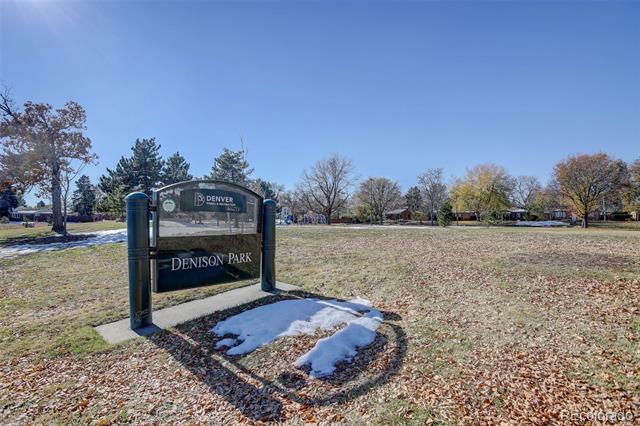 Denison Park sign beside a leaf-covered lawn with patches of snow.