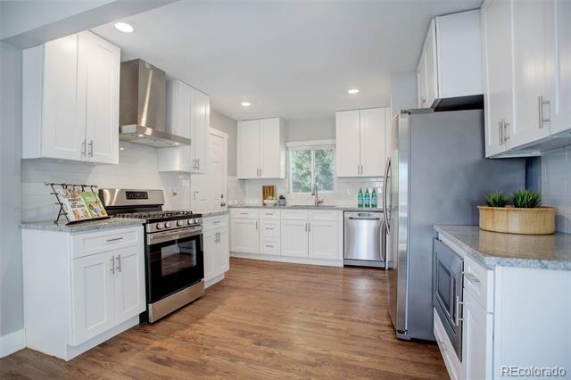 Bright kitchen with white cabinets, stainless steel appliances, and warm wood flooring.