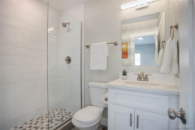 Bathroom with a glass shower, patterned tile floor, and white vanity.