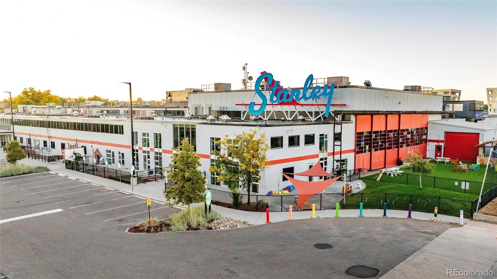 Commercial building with a large Stanley rooftop sign, orange accents, and a fenced lawn.