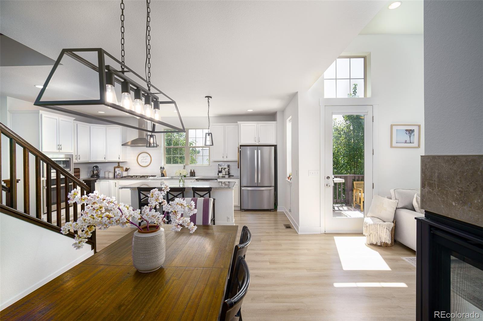 Open-plan kitchen and dining room with white cabinets, a wood table, and a glass door to the deck.