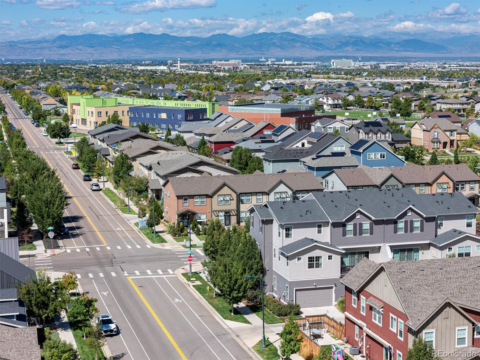 Aerial view of a Denver neighborhood with suburban homes and the Rocky Mountains in the distance.
