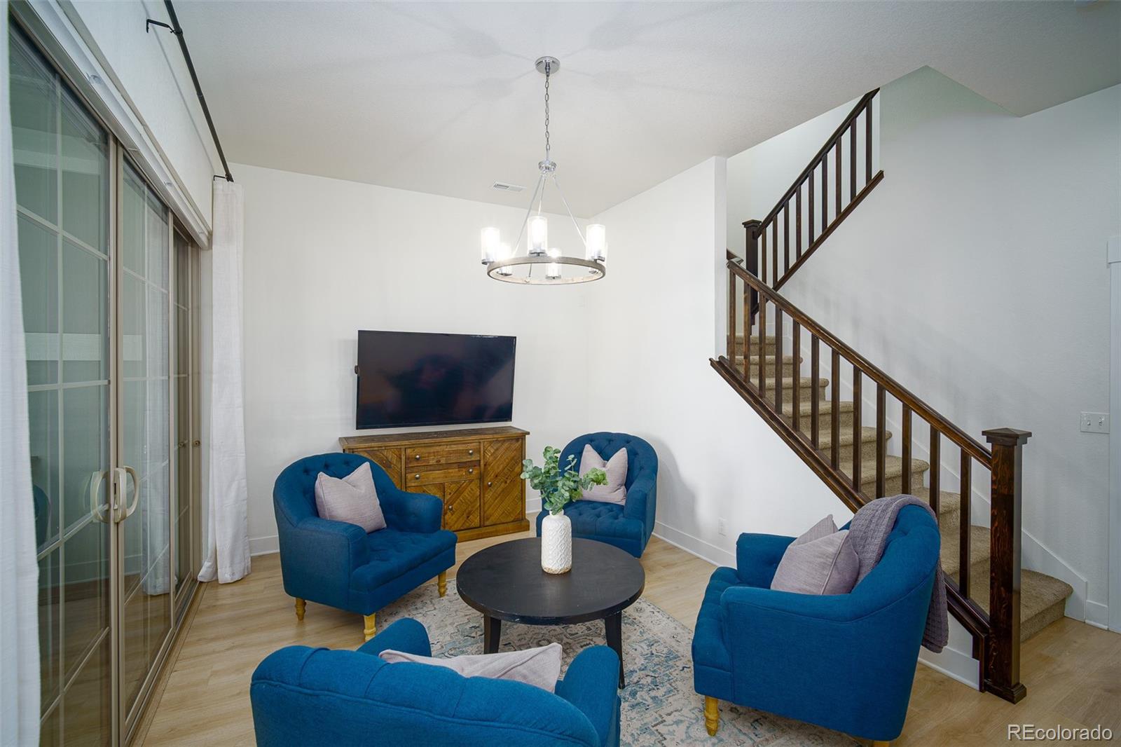 Living room with blue armchairs, sliding glass doors, and a carpeted staircase.
