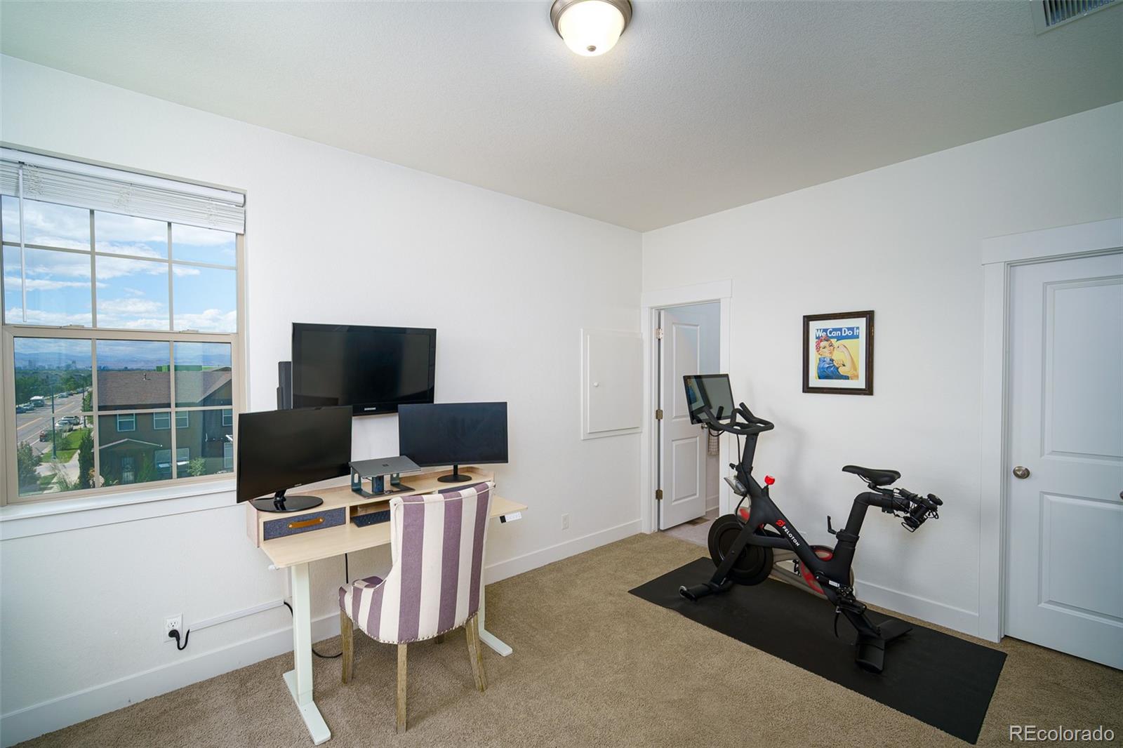 Home office and workout room with a desk, exercise bikes, and a large window overlooking distant mountains.