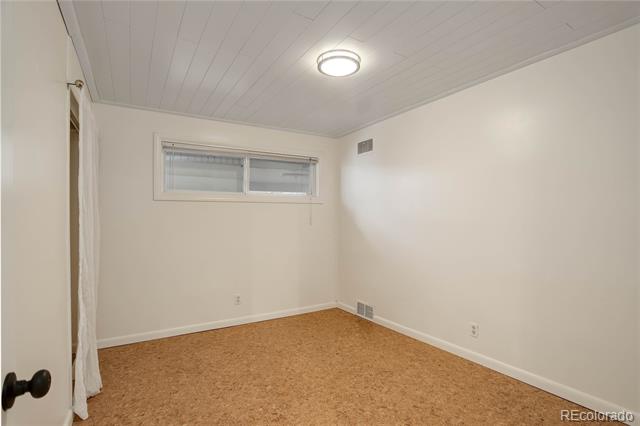Vacant carpeted room with a small horizontal window and a lit ceiling fixture.