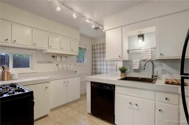 White kitchen with paneled cabinets, a gas range, and a sink in the peninsula.