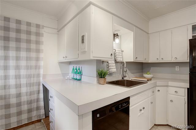 Compact kitchen with white cabinets, brown sink, and gray-and-white checkered curtain.