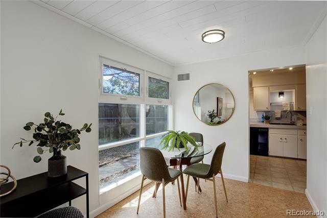 Dining nook with a round glass-top table beside large windows and an open view into the kitchen.