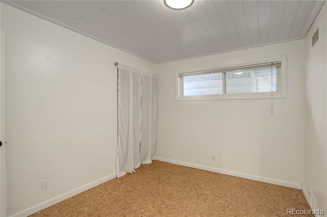 Unfurnished room with tan carpet, a narrow horizontal window, and sheer curtains.