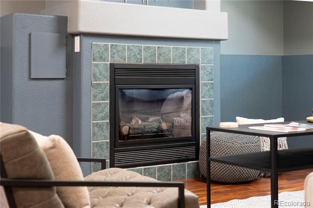Living room fireplace with blue-green tile surround, black insert, and beige upholstered chair.