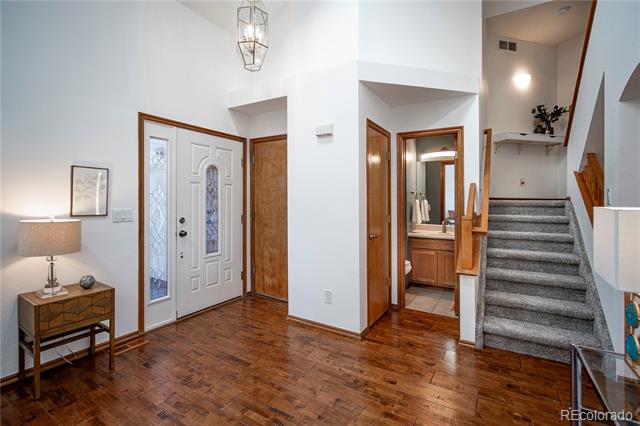 Entry foyer with hardwood floors, a glass-paneled front door, and carpeted stairs.