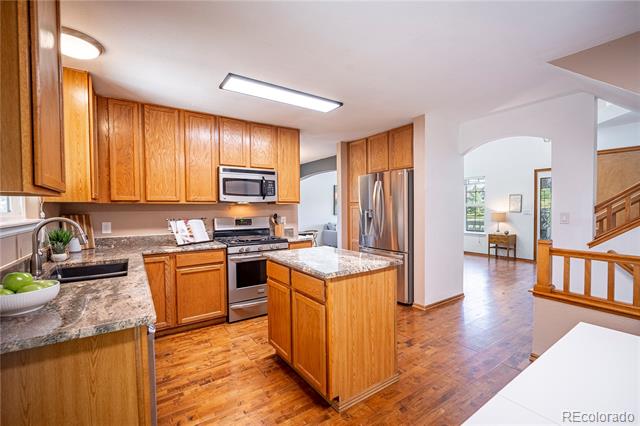 Kitchen with wood cabinetry, granite counters, central island, and stainless steel appliances.