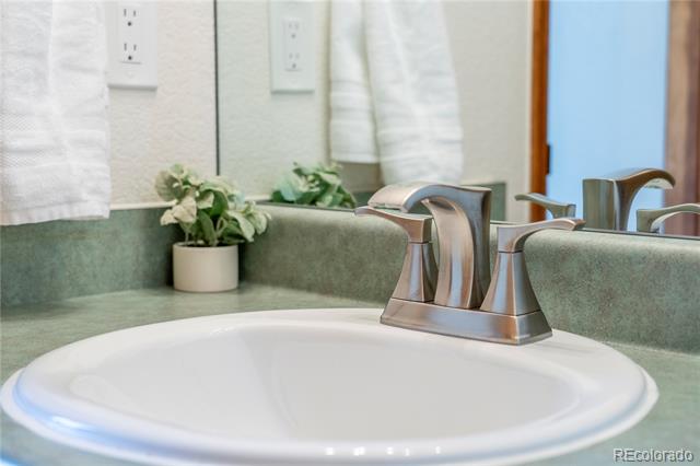 Bathroom vanity with an oval sink, brushed-nickel faucet, green stone counter, and small potted plant.