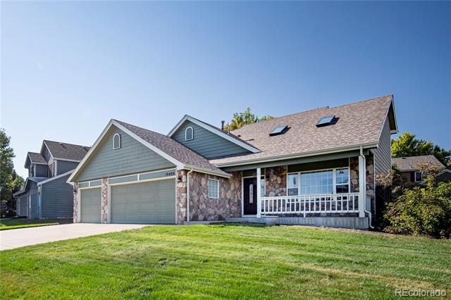 Blue-gray house with stone facade, two-car garage, covered porch, and broad green lawn.