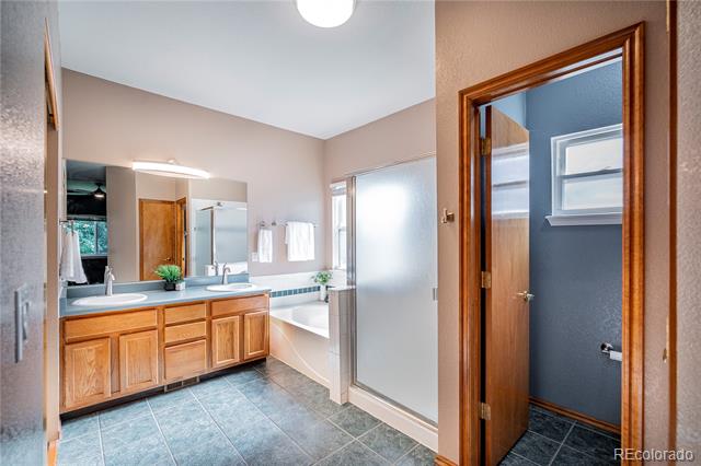 Bathroom with a double-sink wood vanity, tiled floor, and bathtub beside a separate toilet room.