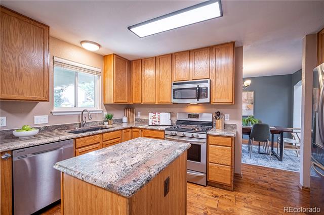Kitchen with oak cabinets, granite counters, a central island, and stainless steel appliances.