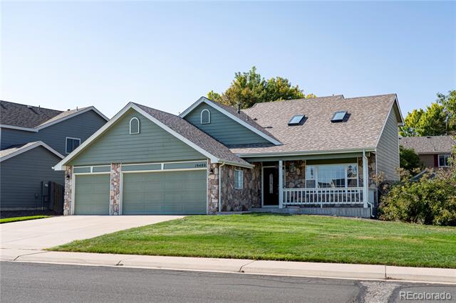 Sage-green house with stone accents, a two-car garage, covered porch, and front lawn.