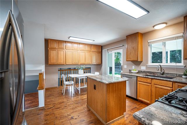 Kitchen with a wood island and stone countertop, wood cabinets, stainless steel appliances, and a small dining table.