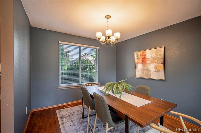 Dining room with a wooden table, upholstered chairs, and a large window with blinds.