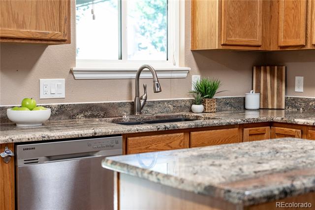 Kitchen with wood cabinets, granite counters, and a sink beneath a window.