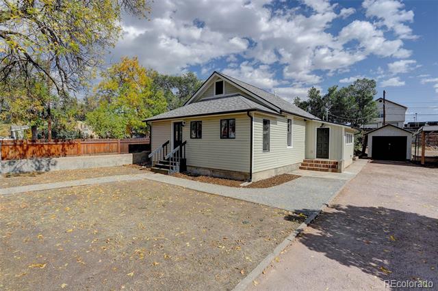 Single-story house with a covered entry, gravel yard, and detached garage.