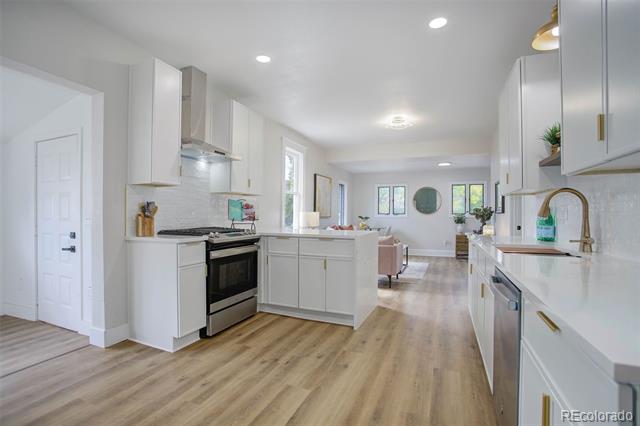 Bright white kitchen with stainless steel appliances, a large island, and light wood floors.