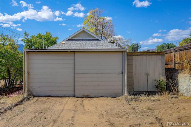 Detached two-car garage with adjoining storage shed and dirt driveway.