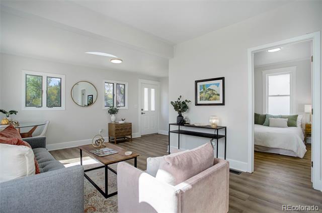 Living room with gray and pink sofas, hardwood floors, and a view into the bedroom.