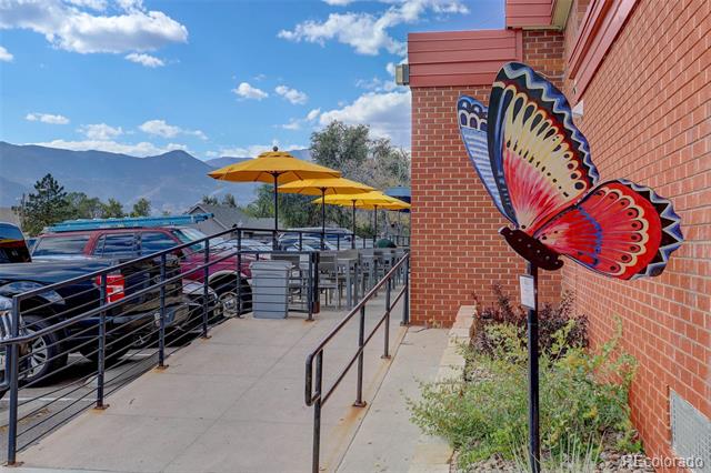 Commercial building patio with yellow umbrellas, metal railing, and mountain views.