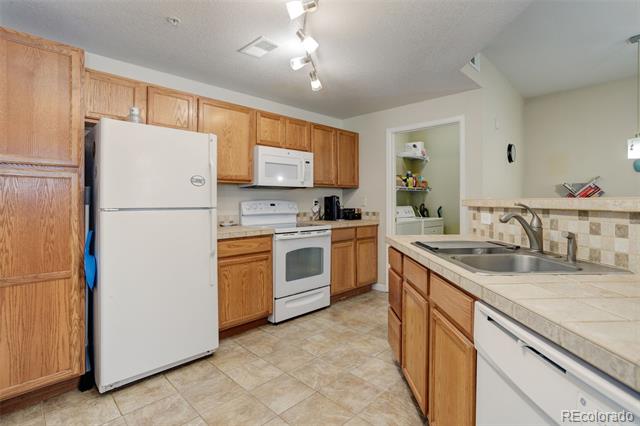 Kitchen with oak cabinets, white appliances, and a tiled floor.