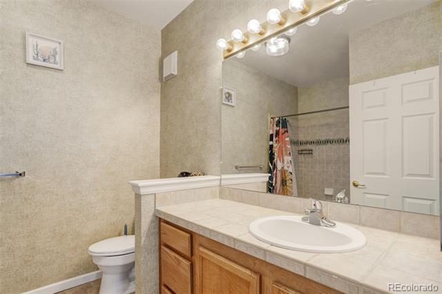 Bathroom with a long wood vanity, oval sink, and mirror reflecting a tub and shower.