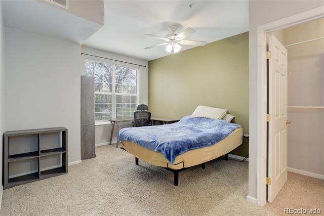 Bedroom with blue bedding, a desk beside a large window, and an open doorway.