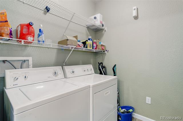 Laundry room with a top-load washer and matching dryer beneath wall-mounted wire shelves.