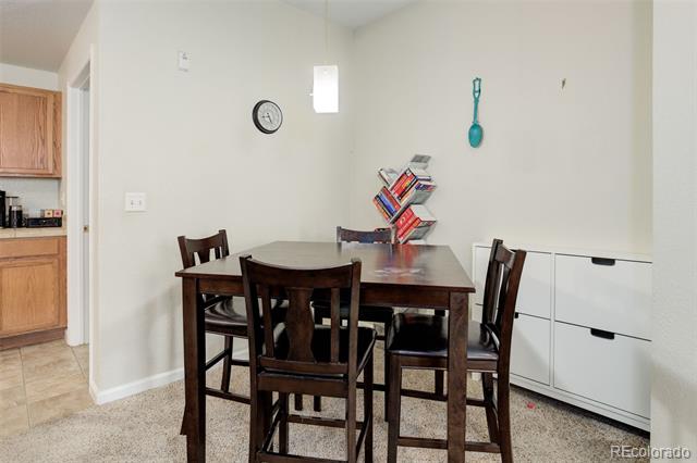 Dining area with a dark wood table and chairs beside a kitchen and built-in storage.